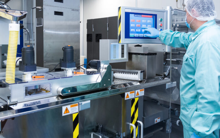 Pharmacy industry factory man worker in protective clothing in sterile working conditions operating on pharmaceutical equipment